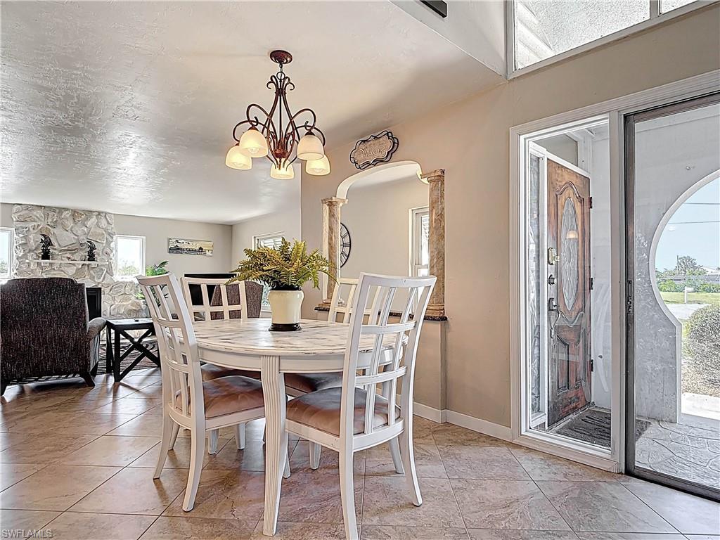 Dining space with a chandelier, light tile patterned flooring, a textured ceiling, and arched walkways