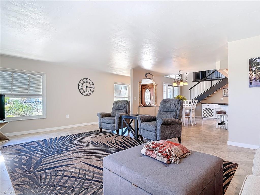 Living area featuring stairway, light tile patterned flooring, and a chandelier