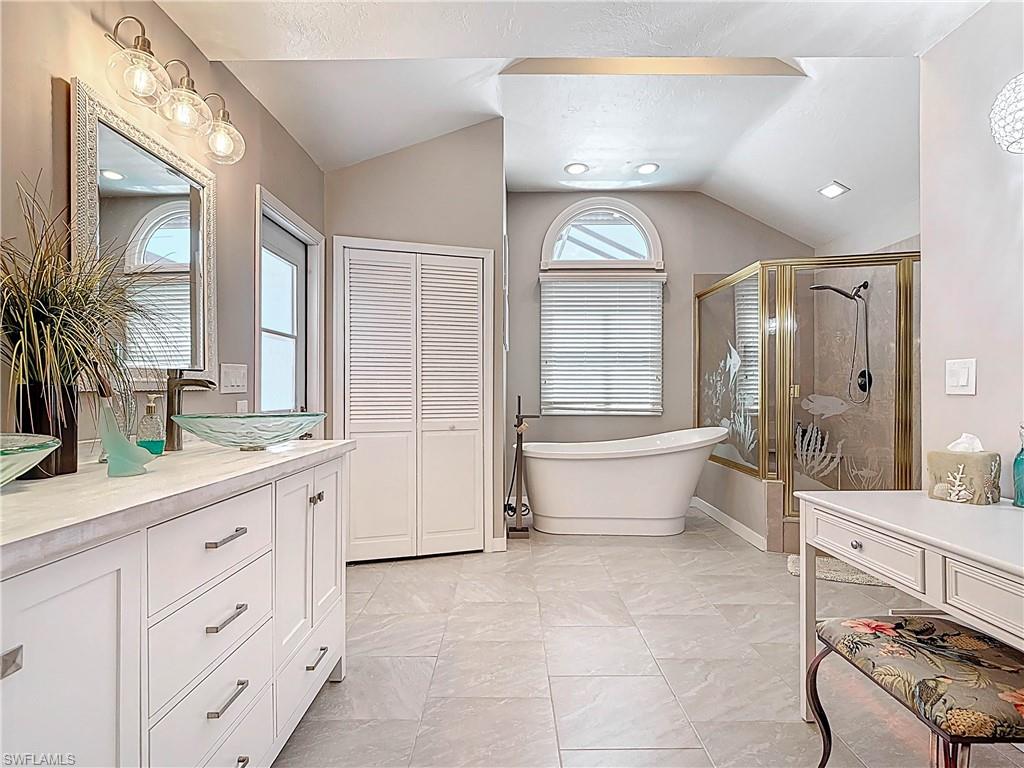 Full bathroom with vaulted ceiling, a stall shower, a freestanding tub, and vanity