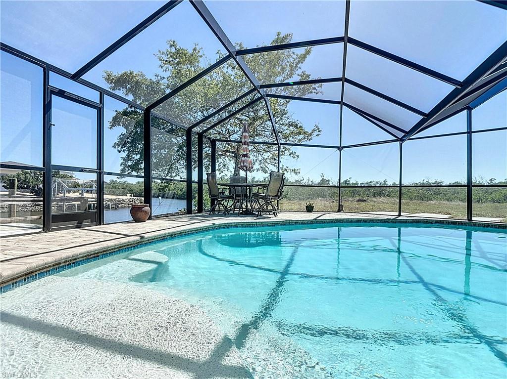 Outdoor pool with a sunroom, glass enclosure, and a patio area