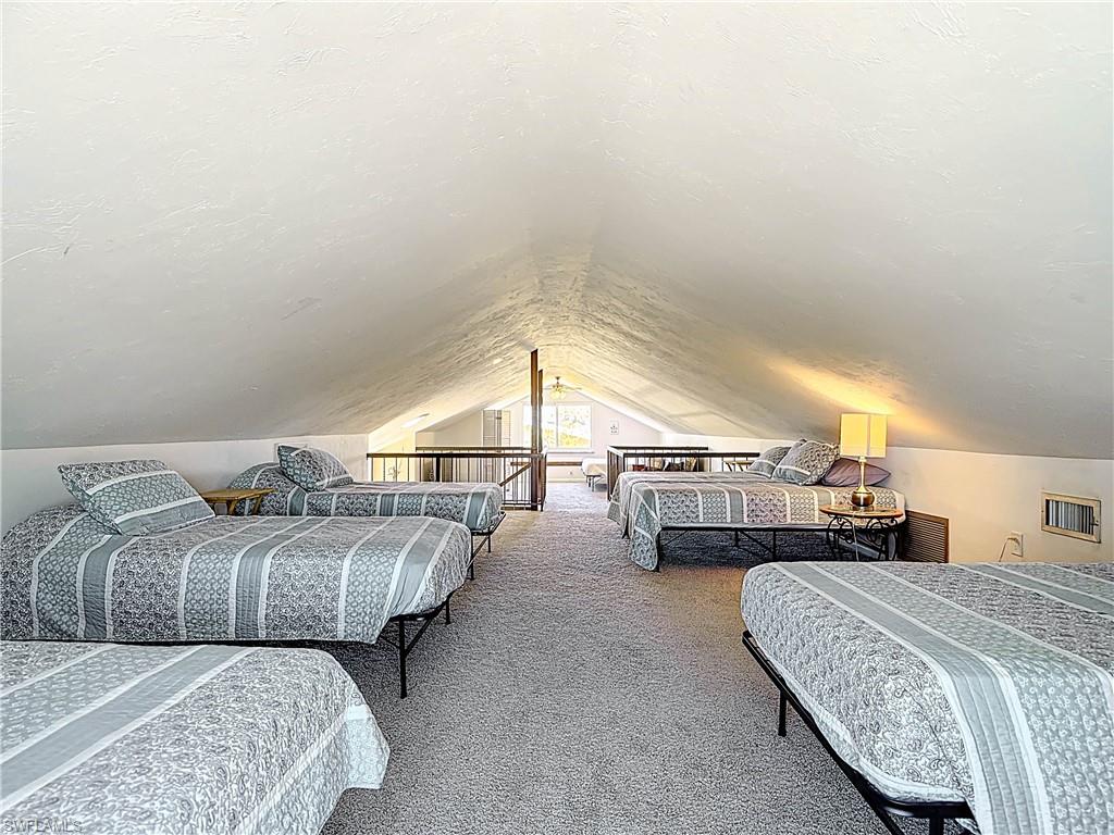 Bedroom featuring vaulted ceiling, a textured ceiling, and carpet
