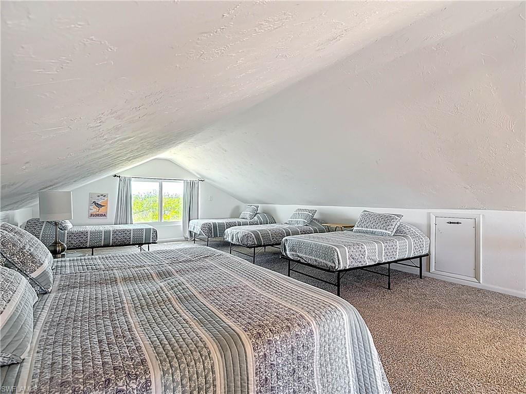 Bedroom with a textured ceiling, vaulted ceiling, and carpet floors