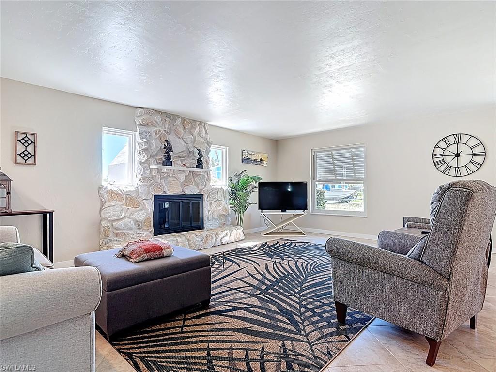 Living room with a stone fireplace, plenty of natural light, a textured ceiling, and tile patterned floors