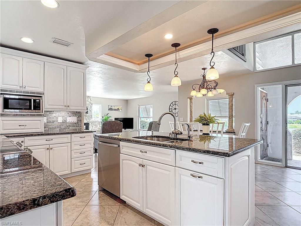 Kitchen with white cabinetry, pendant lighting, a chandelier, a kitchen island with sink, and recessed lighting