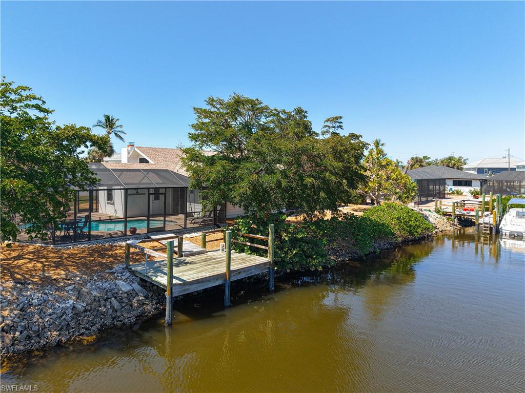 Dock area featuring a sunroom, an outdoor pool, a water view, and a lanai