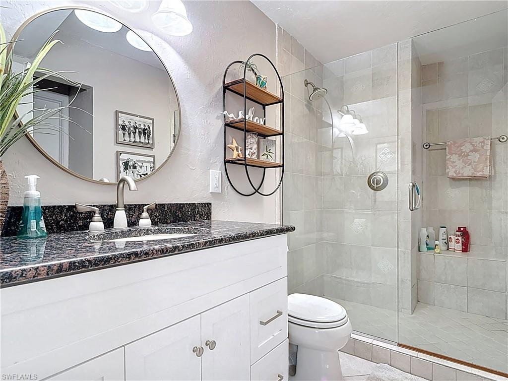 Bathroom featuring vanity, a textured wall, and a shower stall