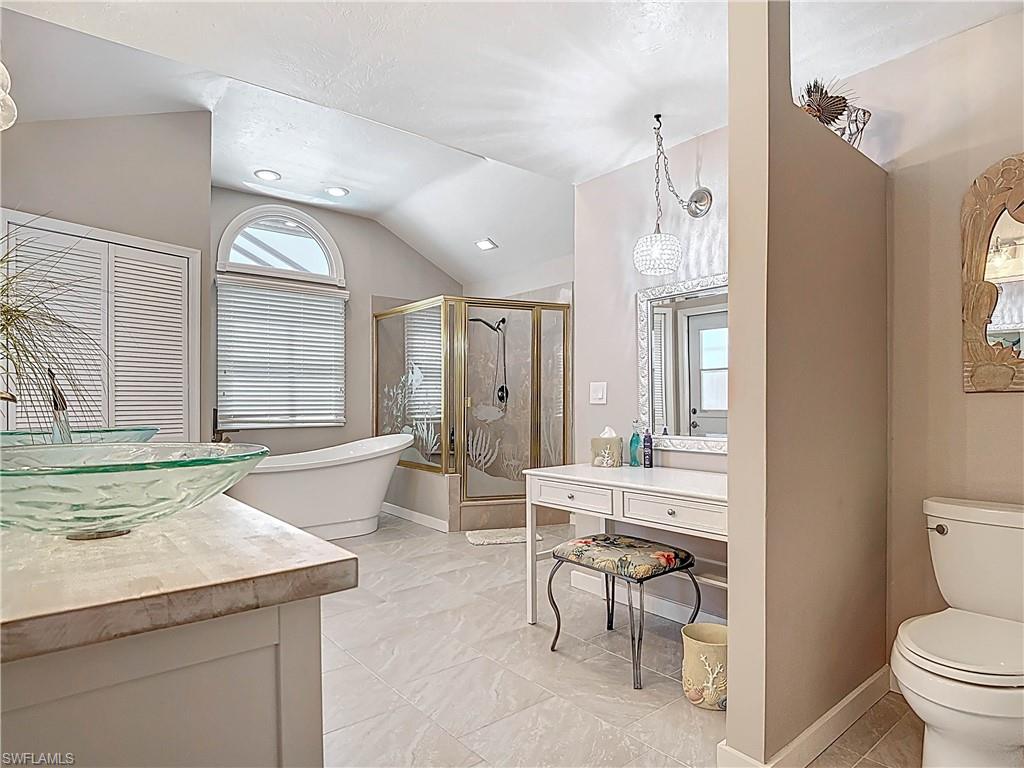 Full bathroom featuring a stall shower, vaulted ceiling, a freestanding bath, vanity, and a chandelier