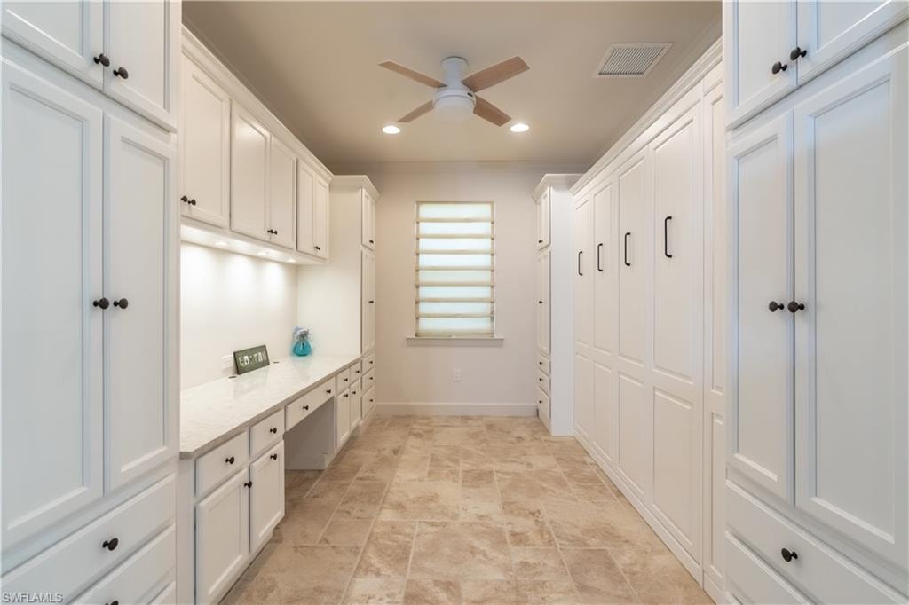 Mudroom with built in desk, recessed lighting, stone finish flooring, and ceiling fan