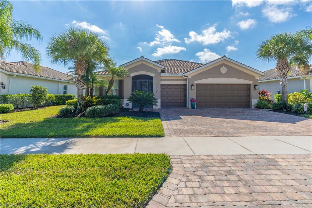 View of front of house featuring a front yard, stucco siding, decorative driveway, and a garage