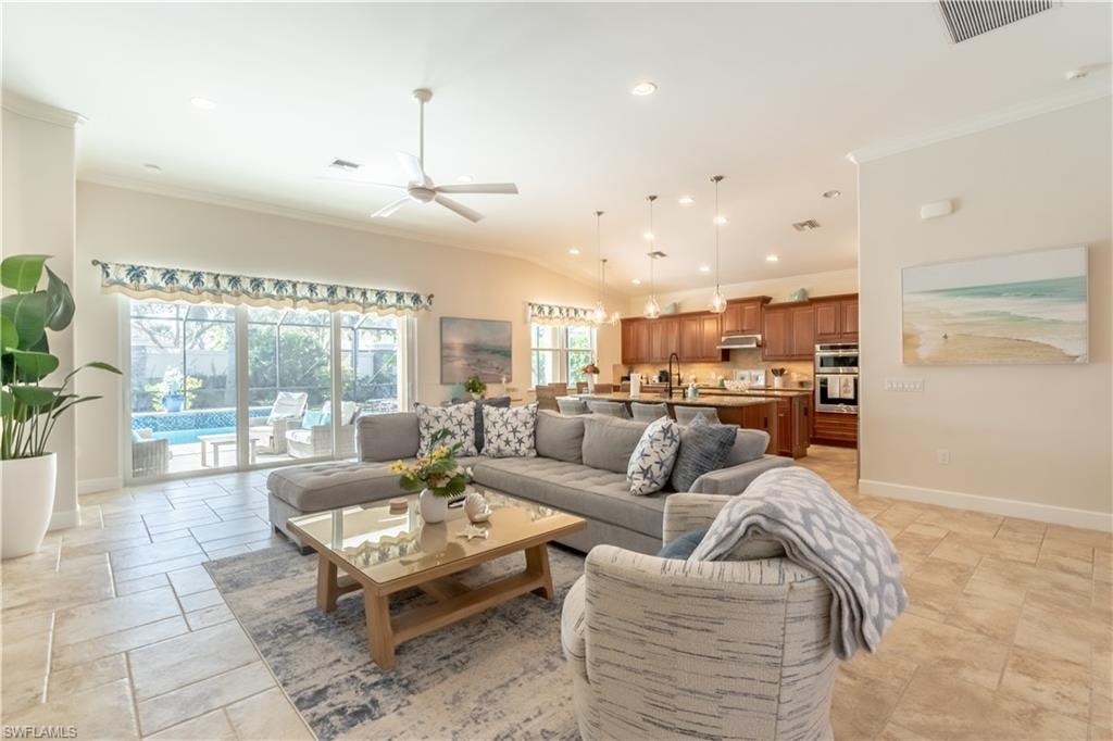Living area with recessed lighting, crown molding, a ceiling fan, stone tile flooring, and lofted ceiling