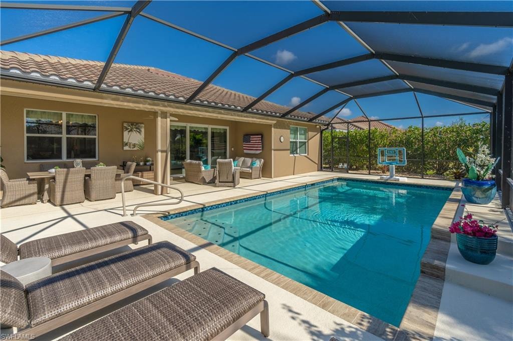 Swimming pool with outdoor lounge area, a sunroom, a patio area, glass enclosure, and outdoor dining space