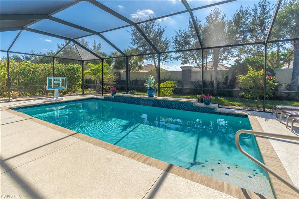 Swimming pool featuring glass enclosure, a sunroom, and a patio area