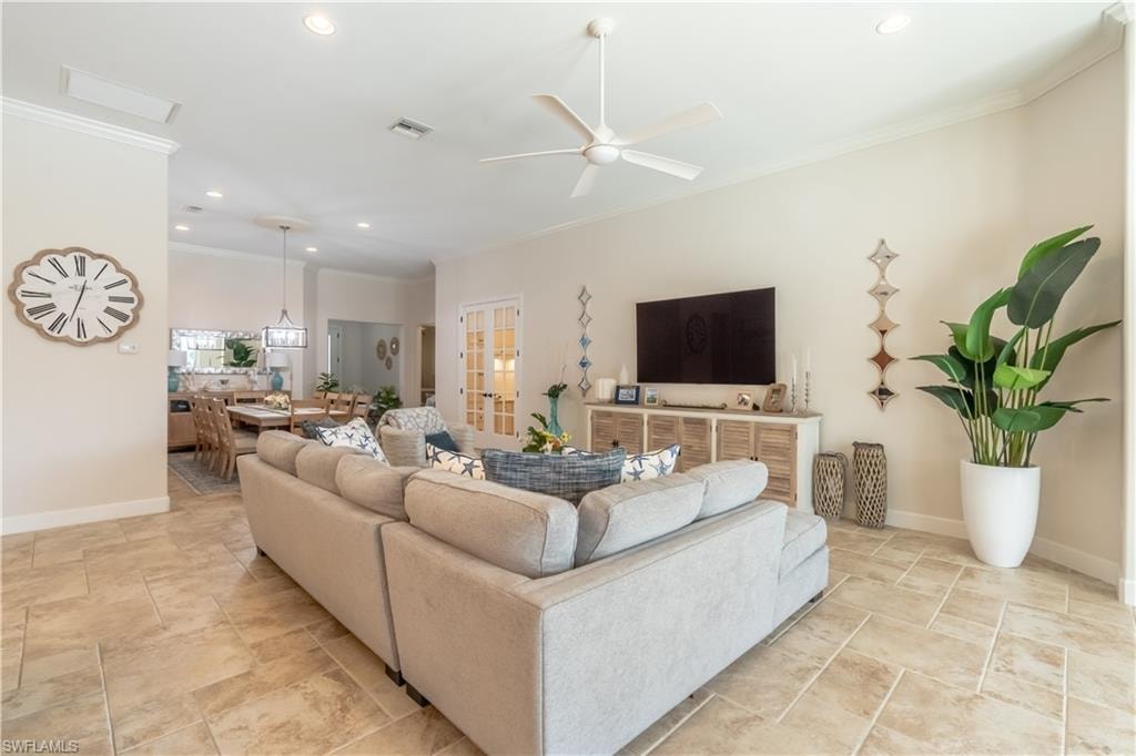 Living room featuring ornamental molding, recessed lighting, ceiling fan, and stone tile flooring