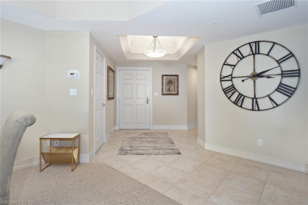 Entryway with ornamental molding, a tray ceiling, a skylight, and light tile patterned floors
