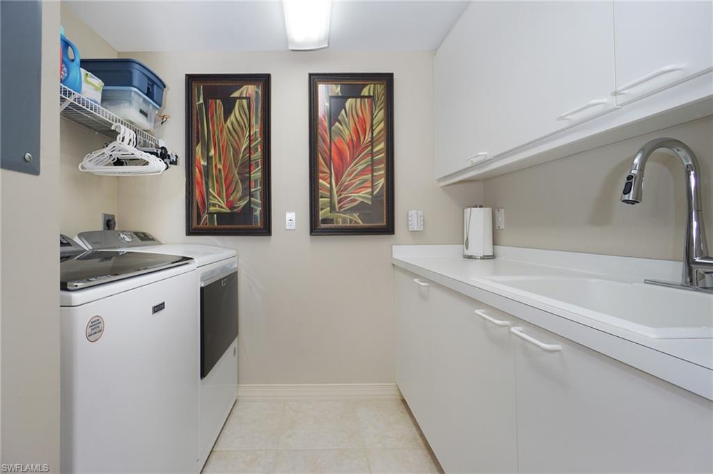 Laundry area featuring cabinets, sink, washing machine and dryer, and light tile patterned floors