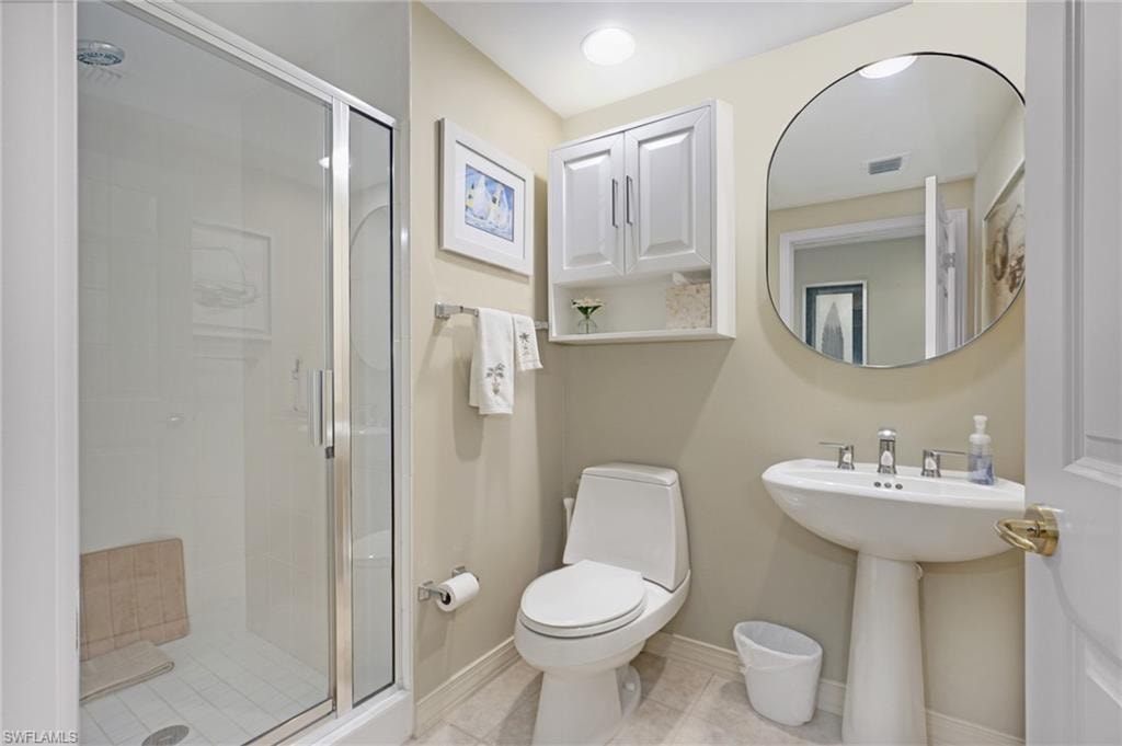 Bathroom featuring sink, toilet, a shower with shower door, and tile patterned flooring