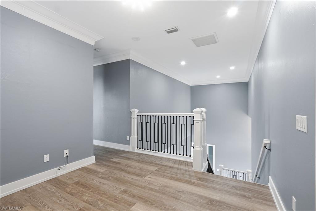 Empty room featuring crown molding, wood finished floors, and recessed lighting