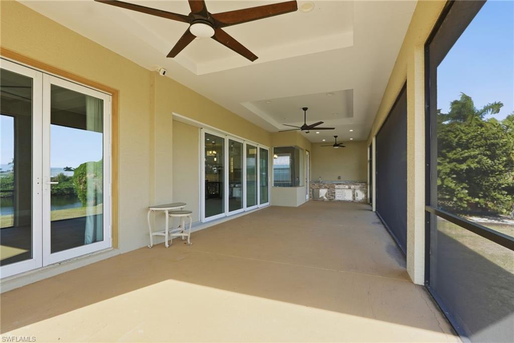 Unfurnished sunroom featuring a ceiling fan, a tray ceiling, and french doors