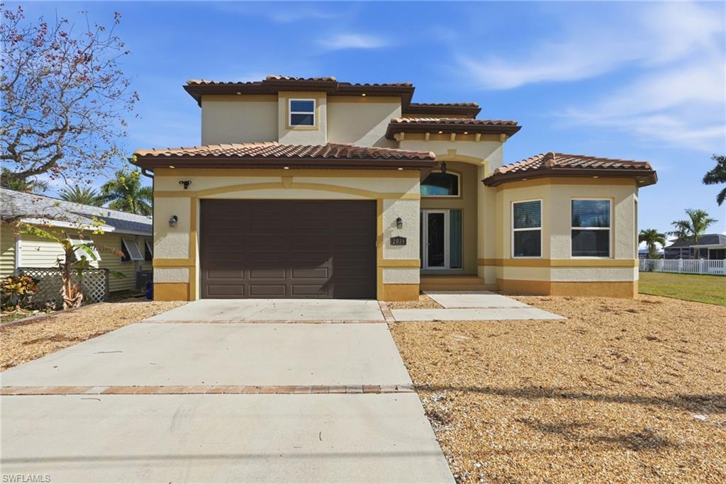 Mediterranean / spanish-style home featuring driveway, a garage, stucco siding, and a tile roof