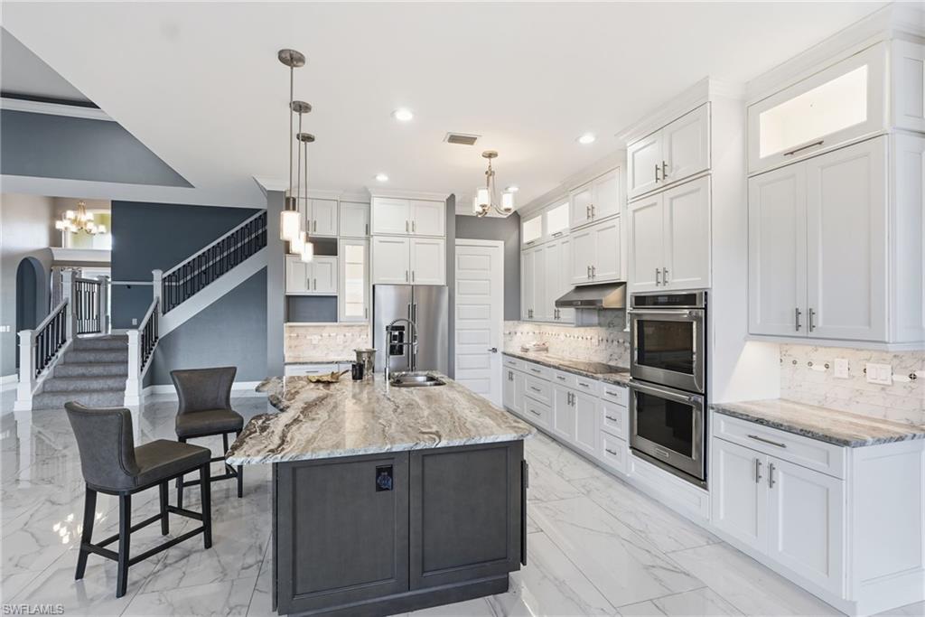 Kitchen with a chandelier, backsplash, white cabinetry, stainless steel appliances, and recessed lighting