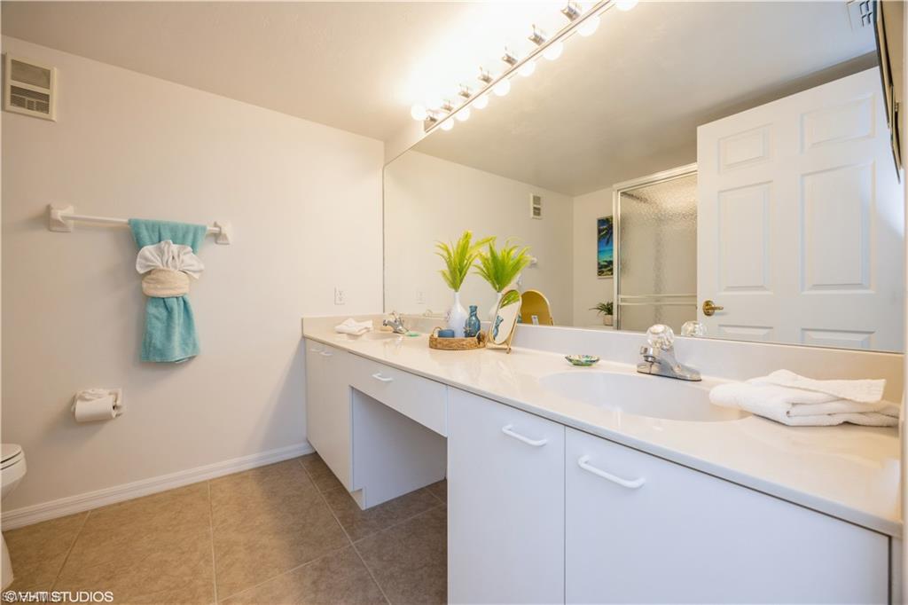 Bathroom with tile patterned floors, a shower with shower door, toilet, and vanity