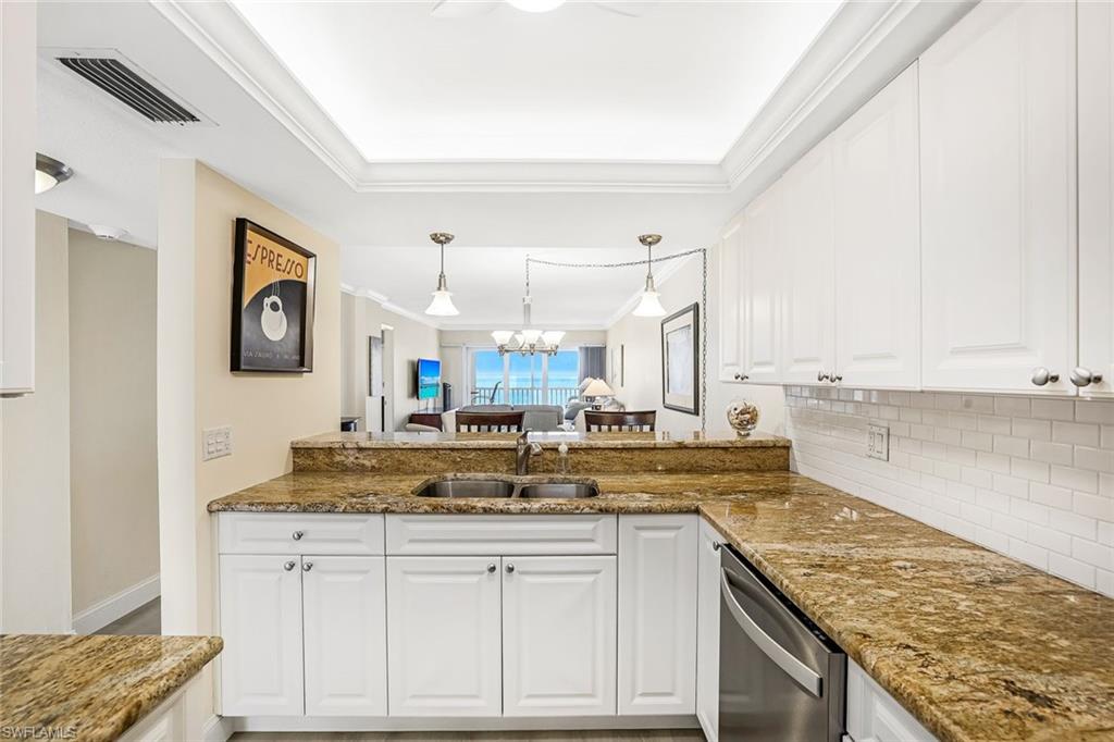 Kitchen with white cabinets, ornamental molding, and dark stone countertops