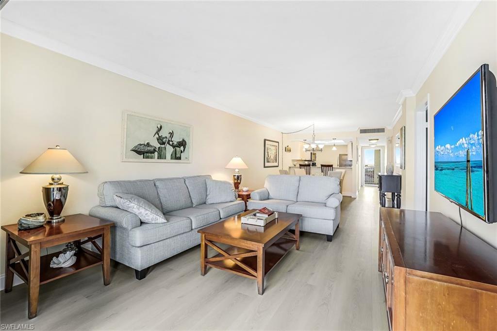 Living area with a chandelier, crown molding, and light wood-style flooring