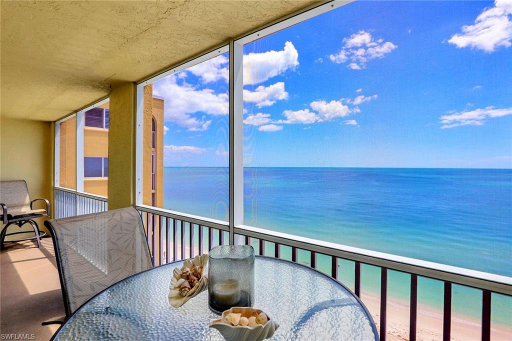 Balcony featuring a sunroom, outdoor dining area, and view of water and beach