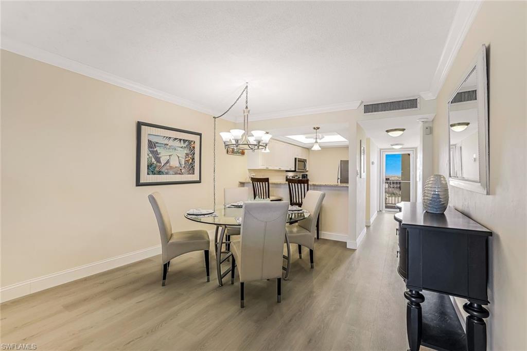 Dining area with ornamental molding, light wood-type flooring, and a chandelier