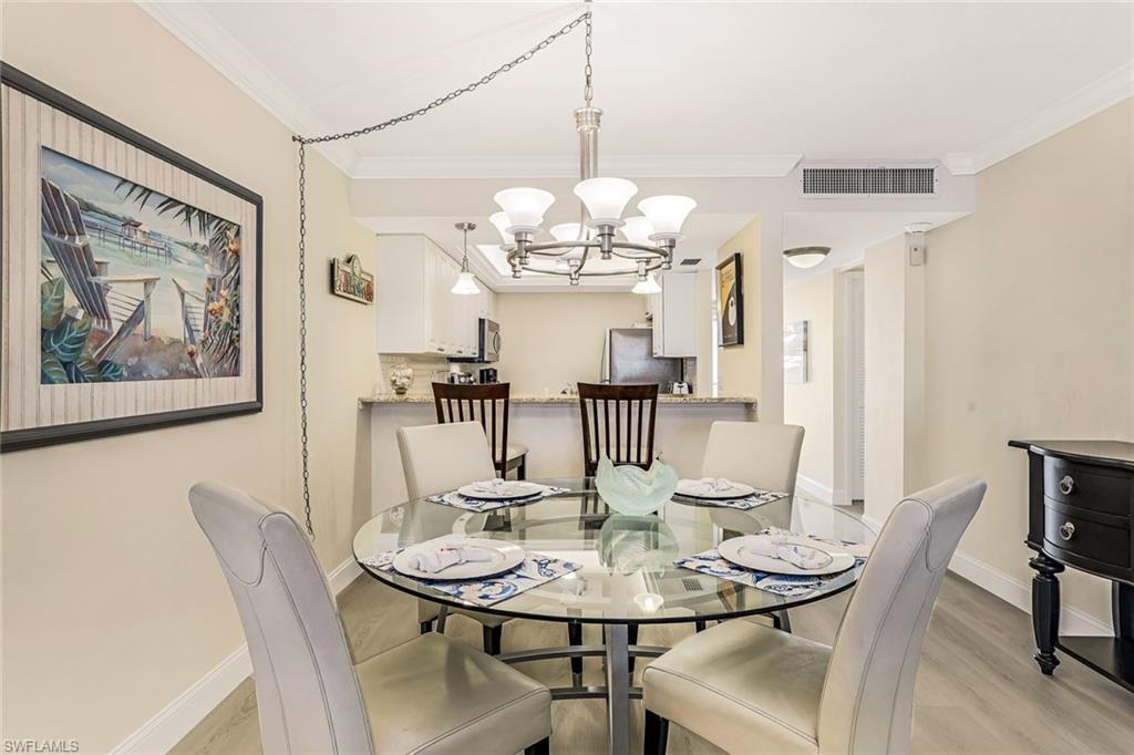 Dining space with light wood-style floors, a chandelier, and crown molding