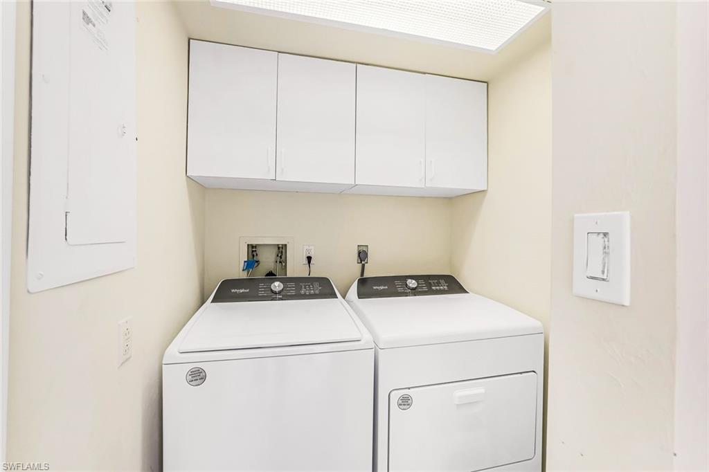 Laundry area with electric panel, cabinet space, and separate washer and dryer