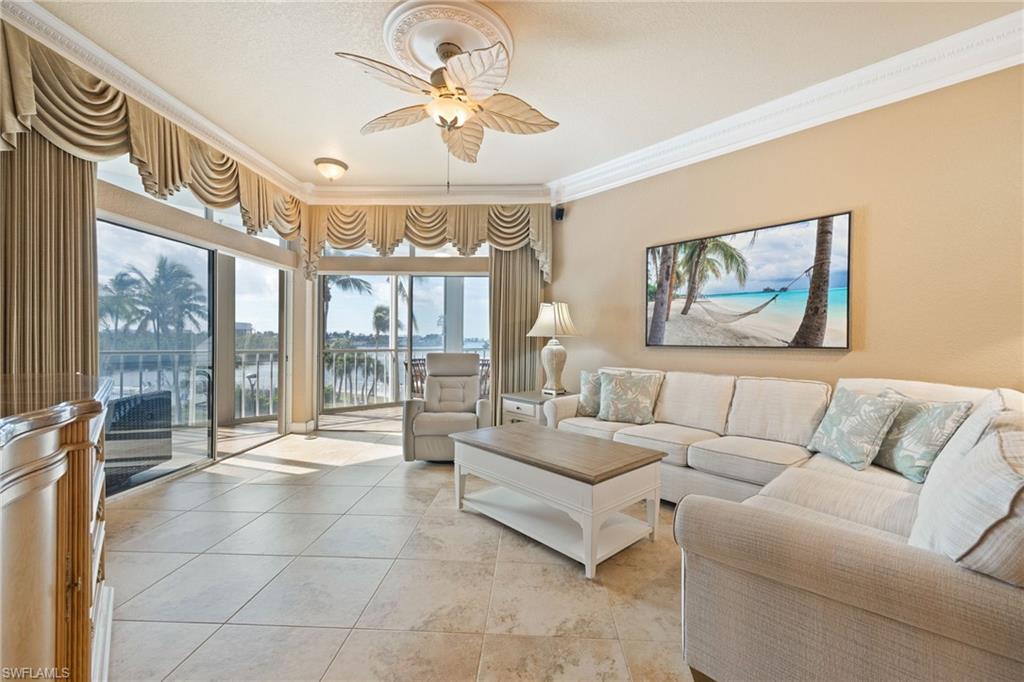 Living room featuring crown molding, a water view, a ceiling fan, and light tile patterned flooring