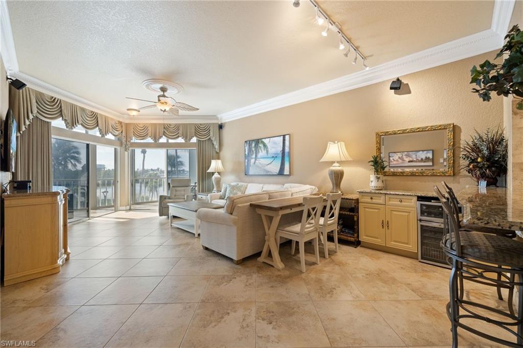 Living room featuring crown molding, a textured ceiling, a ceiling fan, a water view, and track lighting
