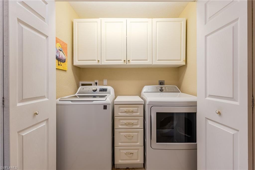 Washroom with washer and clothes dryer and cabinet space