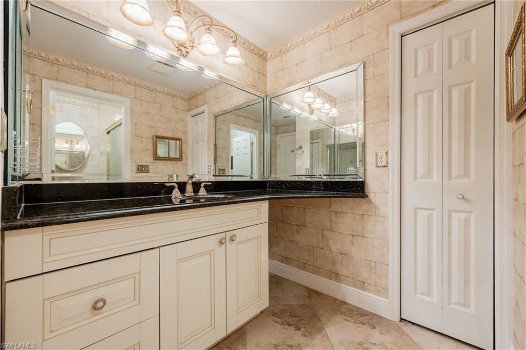 Bathroom featuring vanity, a closet, tile walls, and an enclosed shower