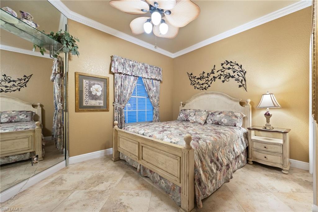 Bedroom with ornamental molding, ceiling fan, and a textured wall