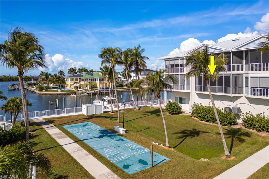 View of community with shuffleboard, a water view, a lawn, and a residential view