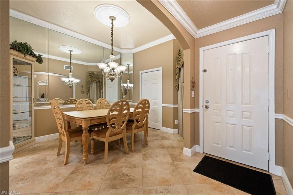 Dining room featuring ornamental molding, arched walkways, and a chandelier
