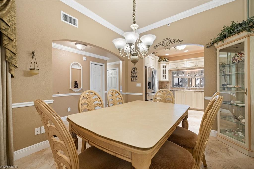 Dining space featuring arched walkways, crown molding, a chandelier, and a textured wall