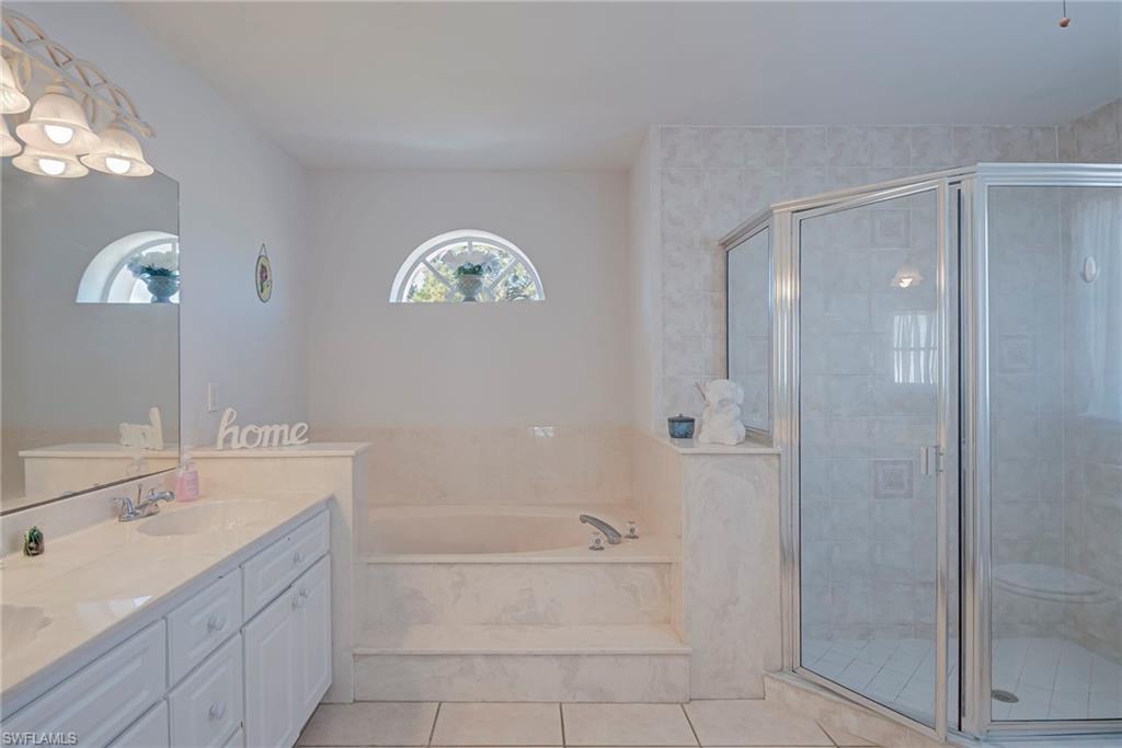Full bathroom with double vanity, a garden tub, a stall shower, and light tile patterned floors
