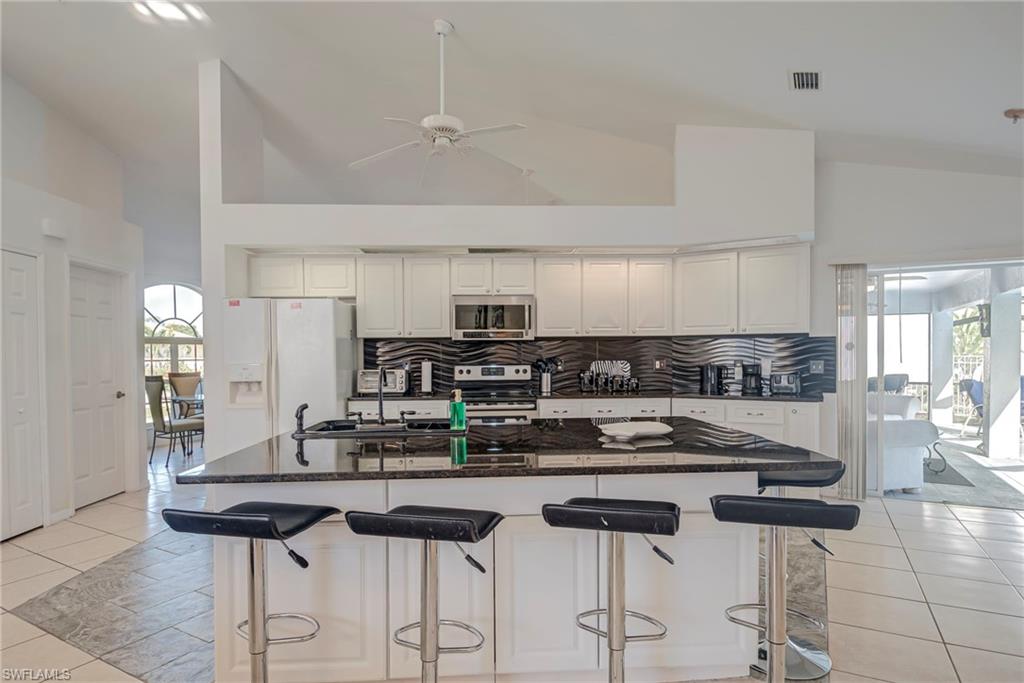 Kitchen with light tile patterned floors, high vaulted ceiling, a kitchen bar, and stainless steel appliances