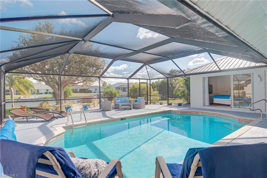 Outdoor pool featuring a sunroom, glass enclosure, and a patio area