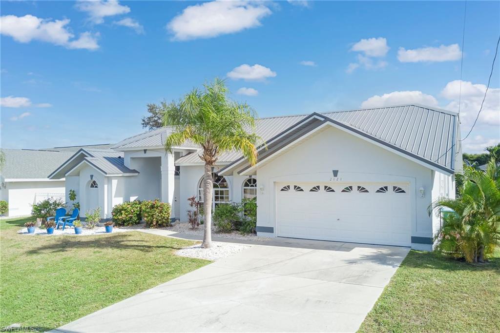 View of front facade with a front lawn, a metal roof, an attached garage, and concrete driveway