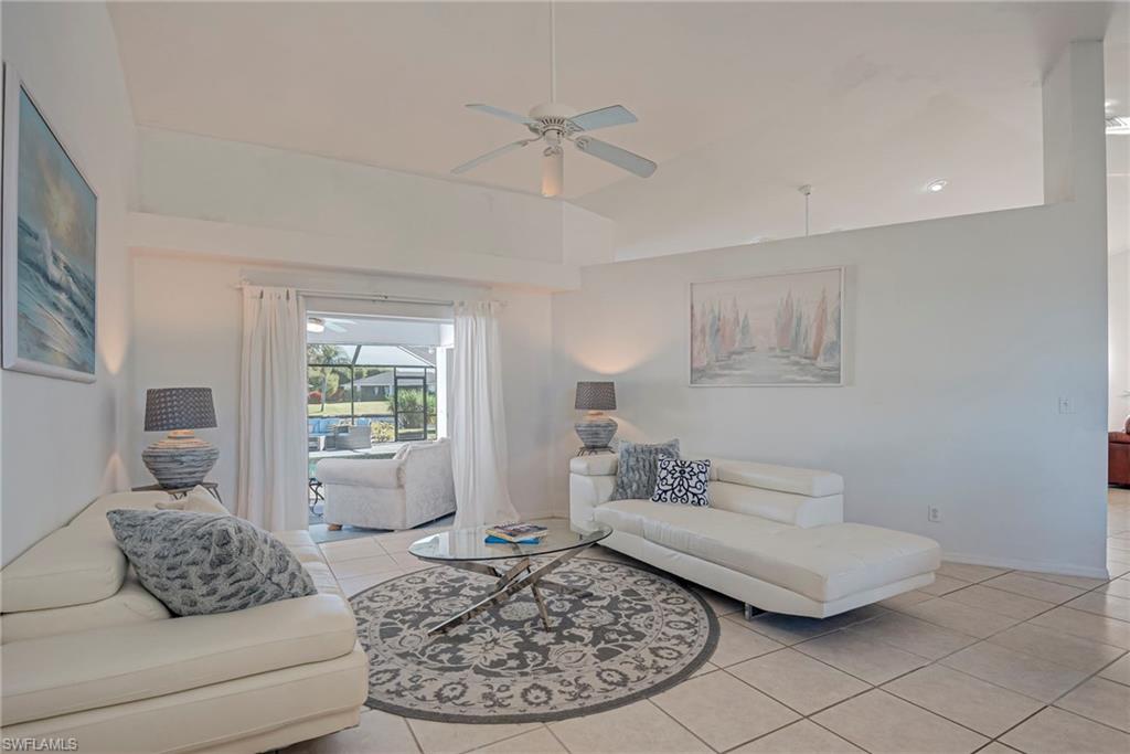 Living area with light tile patterned floors, a ceiling fan, and lofted ceiling