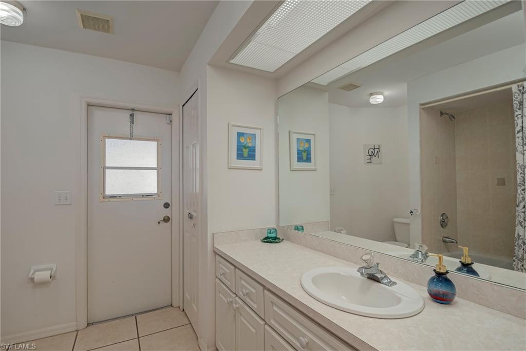 Full bathroom with vanity, light tile patterned floors, and shower / bath combo with shower curtain