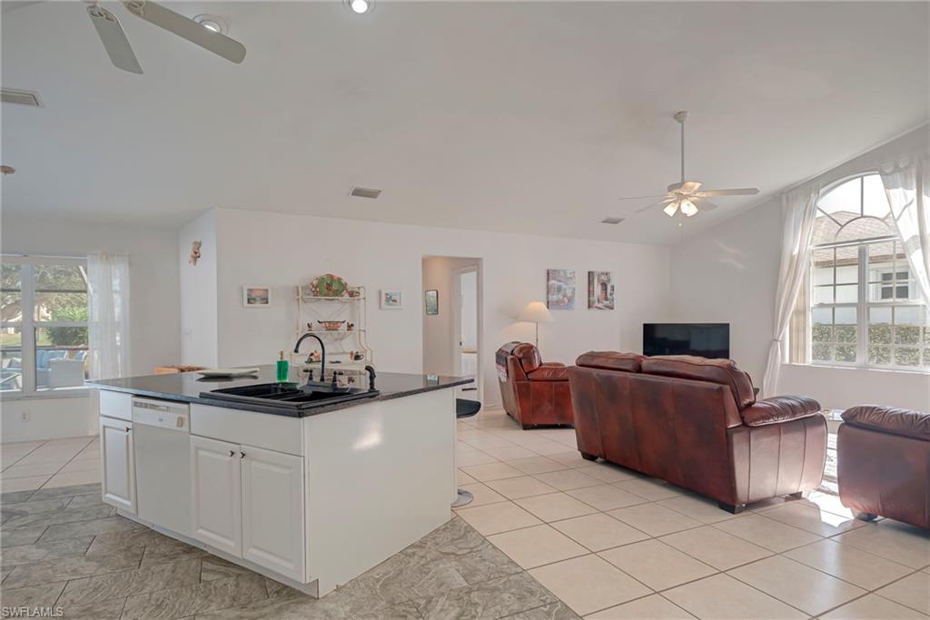 Kitchen featuring ceiling fan, open floor plan, white cabinets, and lofted ceiling