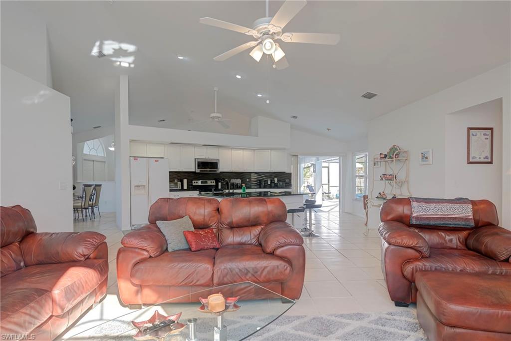 Living area featuring light tile patterned flooring, high vaulted ceiling, and a ceiling fan