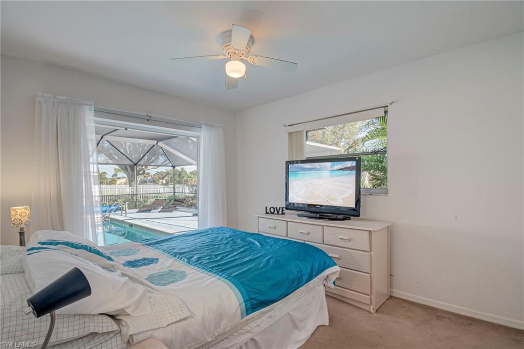 Bedroom with access to exterior, multiple windows, light colored carpet, and ceiling fan