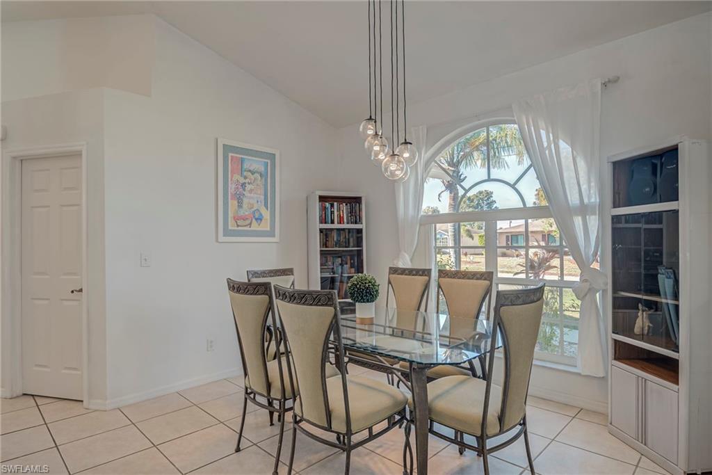 Dining area featuring vaulted ceiling, light tile patterned floors, and a chandelier