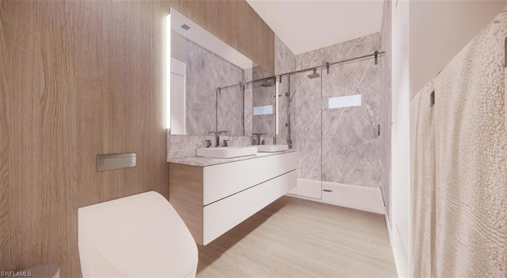 Bathroom featuring a marble finish shower and double vanity